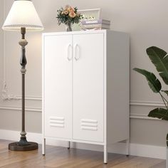 a white cabinet sitting next to a lamp on top of a hard wood floor