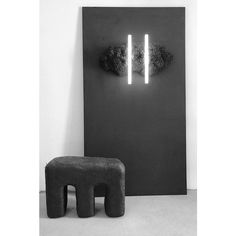 a black and white photo of an elephant stool in front of a wall with two lights on it