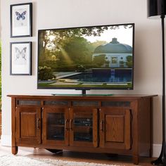 a flat screen tv sitting on top of a wooden entertainment center in a living room