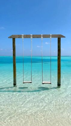 two empty swings in the middle of clear blue water