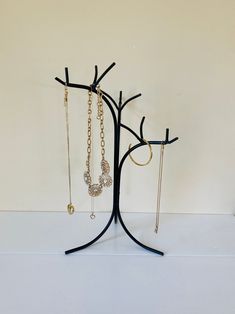 three pairs of earrings are hanging on a black tree with gold chains and dangling earring hooks