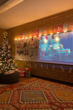 a christmas tree in front of a projector screen with santa clause lights on it