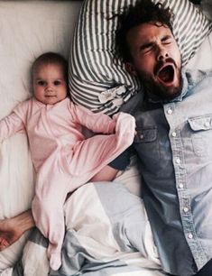 a man laying on top of a bed next to a baby