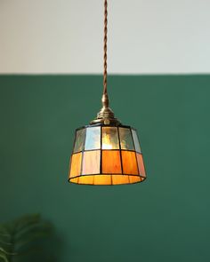 a lamp hanging from a ceiling with a green wall in the background