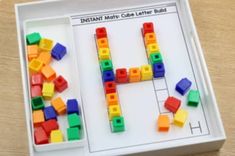 a white tray filled with colorful legos next to a letter h