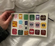 a person is holding an open book with stickers on it, and the pages are covered in different colors