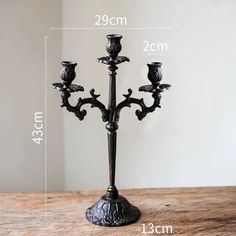 a black candelabra with three candles on it and measurements for each candle holder