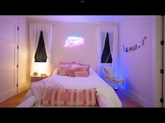 a white bed sitting in a bedroom under a neon sign