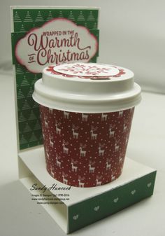 a cup of coffee sitting on top of a table next to a christmas greeting card