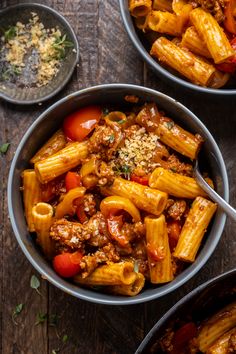 two bowls filled with pasta and meat on top of a wooden table