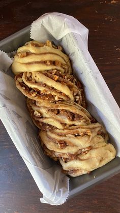 some kind of food that is sitting in a tray on a wooden table with napkins