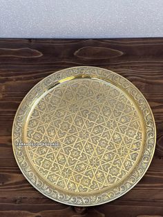 a gold plate with an intricate design on the bottom is sitting on a wooden table