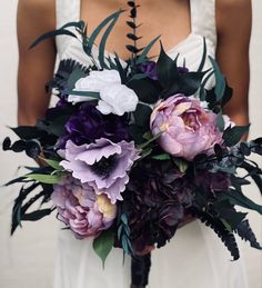 a bride holding a purple and white bouquet