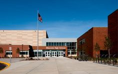 an empty school building with a flag flying in the wind and fenced off area