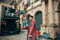 a man standing in front of a building with balloons