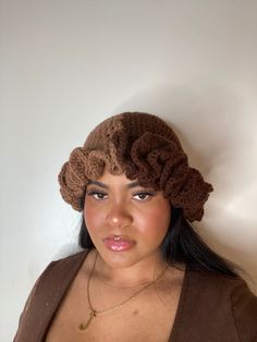 a woman wearing a brown knitted hat with flowers on it's brim