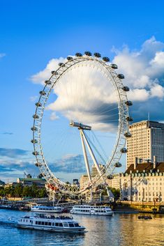 a large ferris wheel in the middle of a body of water next to tall buildings