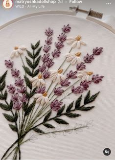 a close up of a embroidery on a white cloth with purple and yellow flowers in it