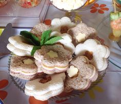 there are many small sandwiches in the bowl on the table with fruit and candy nearby