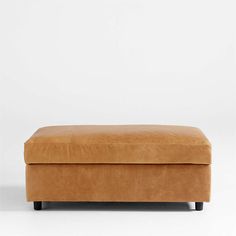 a tan leather ottoman sitting on top of a white floor