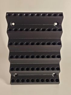 a stack of black plastic blocks on a white surface with holes in the middle and bottom