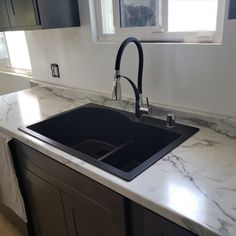 a kitchen with marble counter tops and black faucet