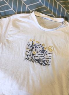 a white t - shirt with an image of a tree and sun on the front