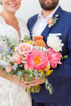 a bride and groom pose for a wedding photo with flowers in their bouquets on their arms