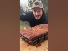 a man holding a knife next to a large piece of meat on a cutting board