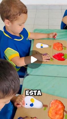 two young boys sitting at a table making crafts