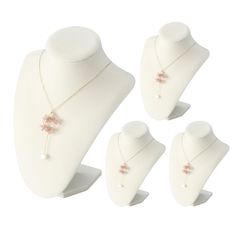 three white mannequins with necklaces on them and one is wearing a pink flower