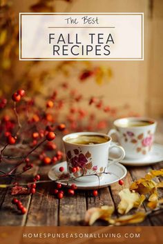 two cups of coffee sitting on top of a wooden table next to leaves and berries