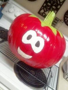 a large tomato with a face drawn on it's side sitting on top of a stove