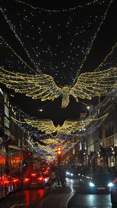 cars driving down the street with christmas lights strung all over it and an eagle hanging from the ceiling