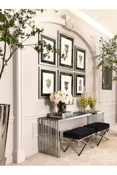 a white room with pictures on the wall and flowers in vases next to it