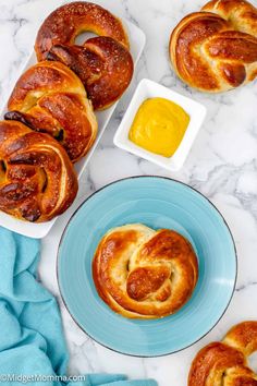 hot cross buns with butter and mustard on a marble countertop next to blue plates