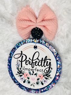 a badge with the words perfectly imperfected on it and a pink bow hanging from it