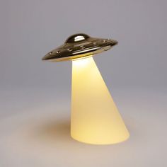 an alien lamp is lit up in the shape of a flying saucer on a gray background