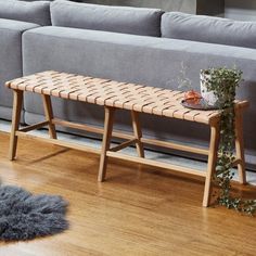 a wooden bench sitting on top of a hard wood floor next to a gray couch