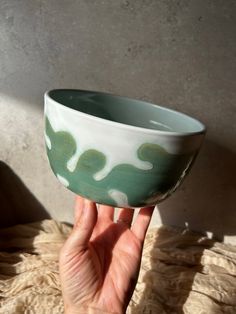 a hand holding up a green and white bowl