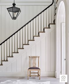 a chair sitting in front of a staircase next to a light on top of a table