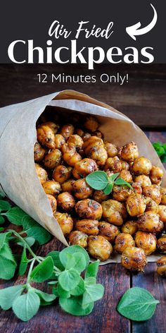 a bag full of chick peas sitting on top of a wooden table next to green leaves