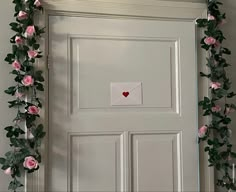 a white door decorated with pink roses and an envelope that says love written on it