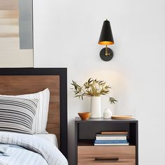 a bed with two nightstands and a lamp on the wall next to each other