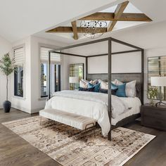 a bedroom with four poster bed and white walls