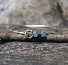 🌟PLEASE READ the following description before making your purchase.  Note measurements and size reference photos. Aquamarine sterling silver bangle bracelet Two natural 6mm aquamarine are set in pure silver on a 2.6mm round spring closure bangle bracelet. Go here for the matching cuff shown in the photos... https://www.etsy.com/listing/1319740649/aquamarine-sterling-silver-cuff-bracelet This item is made to order.  The stones are natural, slight variations will occur. ♥ PLEASE measure your wrist with a soft tape measure or string at the smallest part (between your hand and wrist bone). Select that measurement from the DROP DOWN MENU on the right. I will make the proper adjustments to ensure a comfortable fit. Blue Stone Bracelet, Sterling Silver Bangle Bracelets, Aquamarine Jewelry, Silver Bangle Bracelets, Birthstone Bracelets, Sterling Silver Bangles, Sterling Silver Cuff, Silver Cuff Bracelet, Silver Cuff