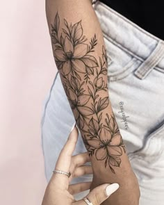 a woman's arm with a flower tattoo on the left forearm and right arm