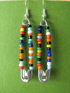 two pairs of colorful beaded earrings hanging from hooks on a green cloth covered surface