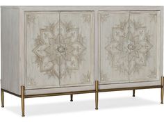 two white and gold painted cupboards with intricate designs on the doors, side by side