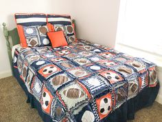 a bed in a bedroom with an orange and blue comforter on top of it